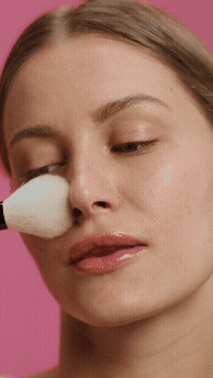 Mulher usando um pincel no rosto